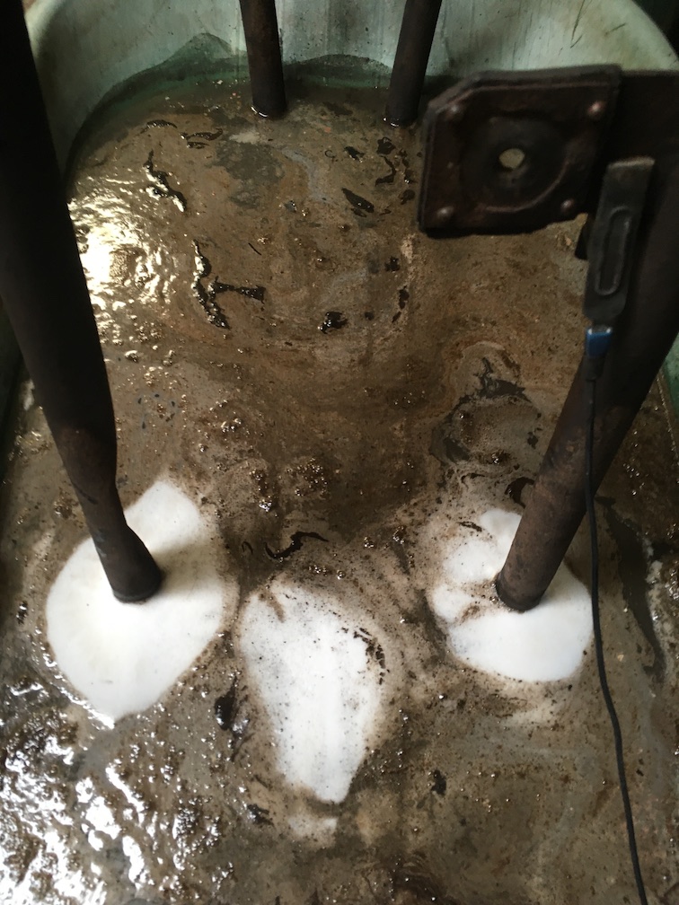Frame sitting in vat of rusty froth